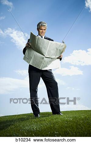 Picture - Low angle view of a businessman reading a newspaper. Fotosearch