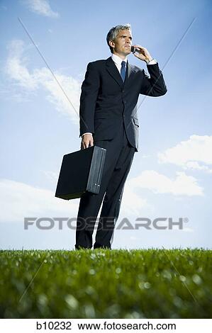 Low angle view of a businessman talking on a mobile phone View Large Photo Image Stock Image - Low angle view of a businessman talking on a mobile phone. Fotosearch