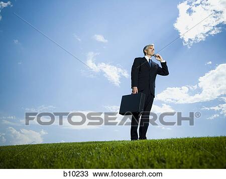 Stock Image - Low angle view of a businessman talking on a mobile phone. Fotosearch
