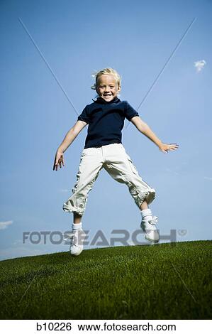 Stock Photograph - Low angle view of a girl jumping and smiling. Fotosearch