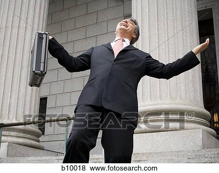Low angle view of a male lawyer holding a briefcase and laughing View Large Photo Image Stock Photo - Low angle view of a male lawyer holding a briefcase and laughing. Fotosearch