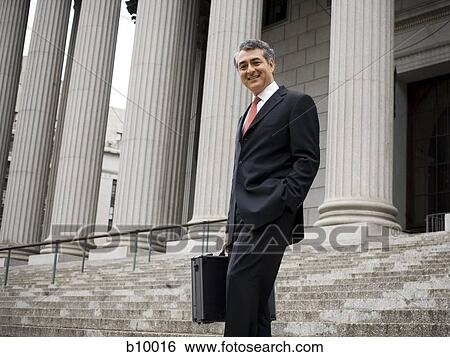 Low angle view of a male lawyer standing on the steps of a courthouse and smiling View Large Photo Image Stock Photograph - Low angle view of a male lawyer standing on the steps of a courthouse and smiling. Fotosearch