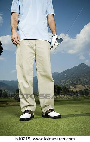 Low angle view of a man holding a golf club on a golf course View Large Photo Image Stock Photo - Low angle view of a man holding a golf club on a golf course. Fotosearch