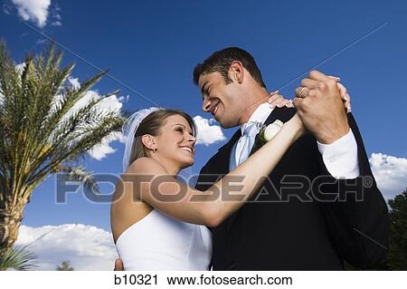 Low angle view of a newlywed couple dancing View Large Photo Image Stock Image - Low angle view of a newlywed couple dancing. Fotosearch