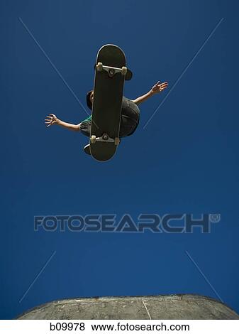 Low angle view of a person jumping with a skateboard View Large Photo Image Stock Photo - Low angle view of a person jumping with a skateboard. Fotosearch