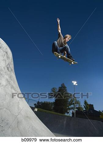 Low angle view of a teenage boy jumping with a skateboard View Large Photo Image Stock Photo - Low angle view of a teenage boy jumping with a skateboard. Fotosearch