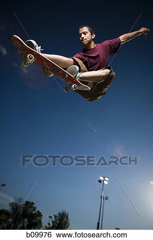 Low angle view of a teenage boy jumping with a skateboard View Large Photo Image Stock Photograph - Low angle view of a teenage boy jumping with a skateboard. Fotosearch