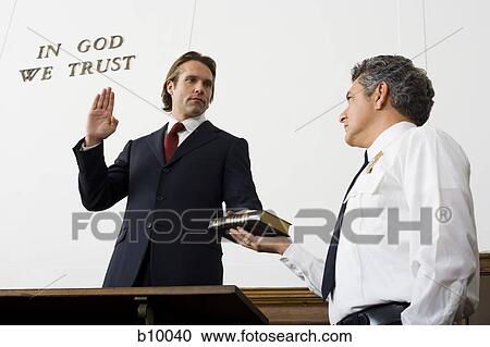 Low angle view of a witness swearing over the Bible View Large Photo Image Stock Image - Low angle view of a witness swearing over the Bible. Fotosearch