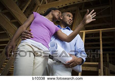 Stock Photo - Low angle view of a young couple looking away. Fotosearch