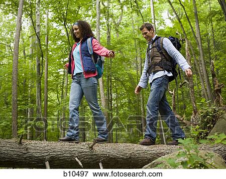Low angle view of a young couple walking on a fallen tree View Large Photo Image Stock Photo - Low angle view of a young couple walking on a fallen tree. Fotosearch