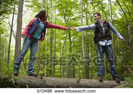Low angle view of a young couple holding hands and walking on a fallen tree View Large Photo Image Stock Photo - Low angle view of a young couple holding hands and walking on a fallen tree. Fotosearch