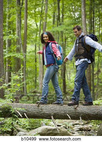 Low angle view of a young couple walking on a fallen tree View Large Photo Image Stock Photo - Low angle view of a young couple walking on a fallen tree. Fotosearch