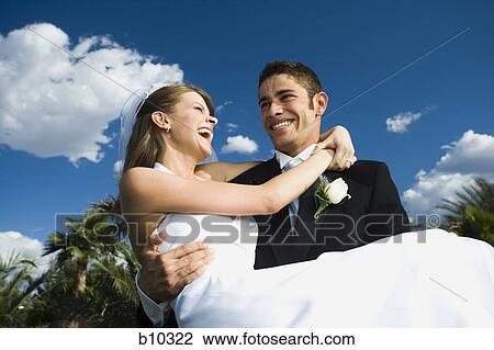 Low angle view of a young man carrying his bride and smiling View Large Photo Image Stock Image - Low angle view of a young man carrying his bride and smiling. Fotosearch