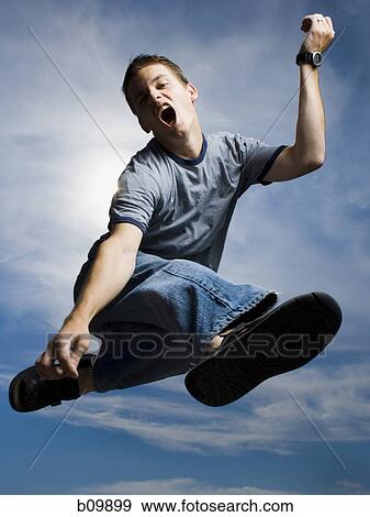 Low angle view of a young man jumping View Large Photo Image Stock Photo - Low angle view of a young man jumping. Fotosearch