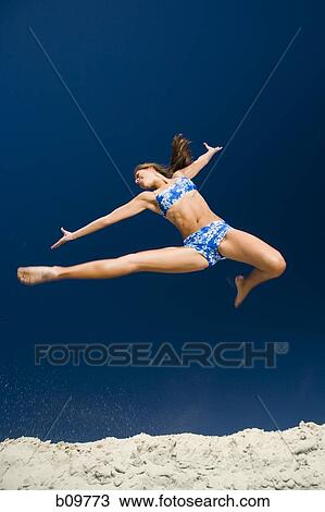 Low angle view of a young woman jumping View Large Photo Image Stock Image - Low angle view of a young woman jumping. Fotosearch