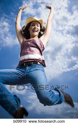 Stock Image - Low angle view of a young woman jumping. Fotosearch