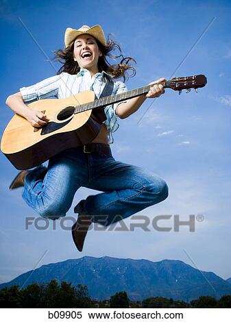 Low angle view of a young woman jumping and playing the guitar View Large Photo Image Stock Photography - Low angle view of a young woman jumping and playing the guitar. Fotosearch