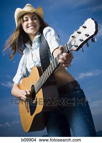 Low angle view of a young woman playing the guitar View Large Photo Image Picture - Low angle view of a young woman playing the guitar. Fotosearch