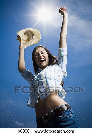 Low angle view of a young woman with her arms raised View Large Photo Image Stock Image - Low angle view of a young woman with her arms raised. Fotosearch