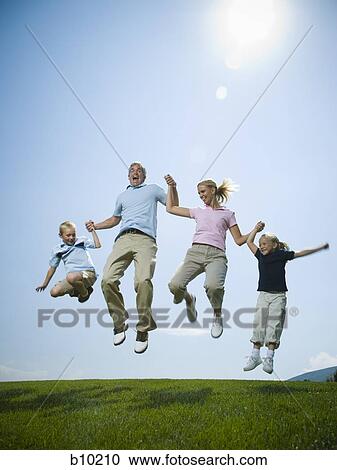 Stock Image - Low angle view of parents and their two children jumping. Fotosearch