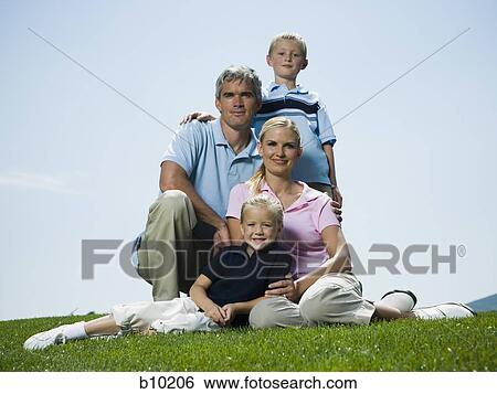 Low angle view of parents and their two children sitting on grass View Large Photo Image Stock Photograph - Low angle view of parents and their two children sitting on grass. Fotosearch