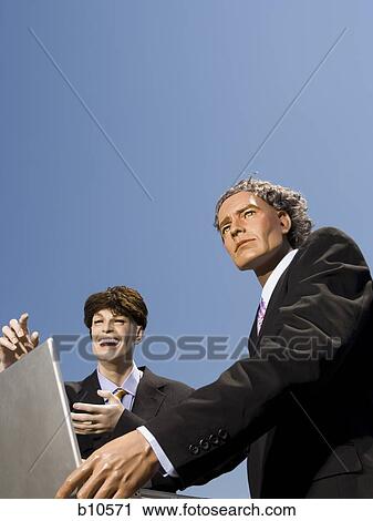 Low angle view of two mannequins portraying businessmen using a laptop View Large Photo Image Stock Image - Low angle view of two mannequins portraying businessmen using a laptop. Fotosearch
