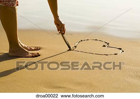 Low section view of a person drawing a heart in the sand on the beach View Large Photo Image Stock Image - Low section view of a person drawing a heart in the sand on the beach. Fotosearch