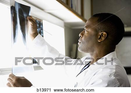 Stock Image - Male doctor looking at chest x-rays. Fotosearch