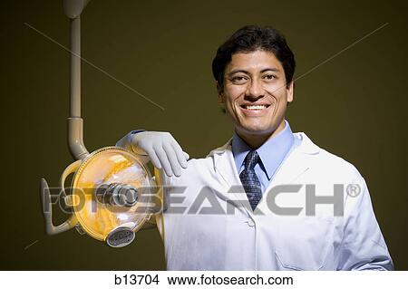 Male doctor or dentist with surgical lamp smiling View Large Photo Image Picture - Male doctor or dentist with surgical lamp smiling. Fotosearch