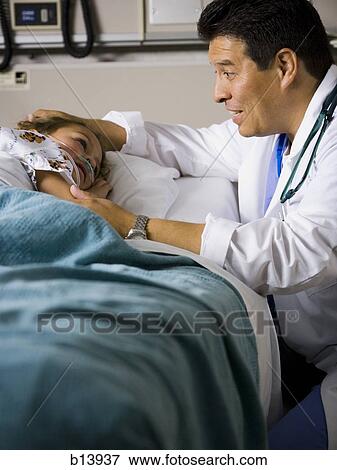 Male doctor talking to young girl in hospital bed View Large Photo Image Stock Photo - Male doctor talking to young girl in hospital bed. Fotosearch