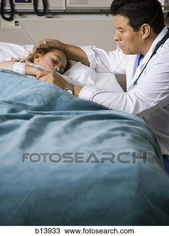 Stock Image - Male doctor with young girl in hospital. Fotosearch