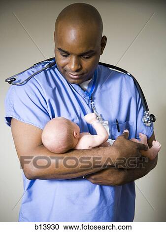 Stock Image - Male nurse or doctor holding newborn baby. Fotosearch