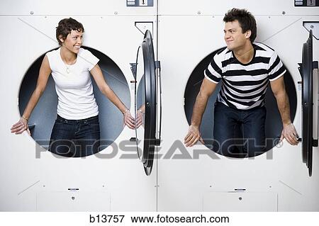 Stock Photo - Man and woman in Laundromat dryers smiling. Fotosearch