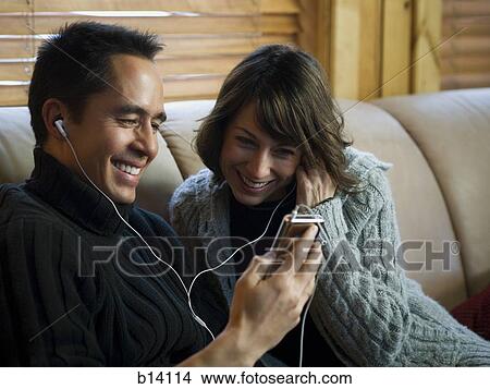 Man and woman on sofa listening to music on mp3 player View Large Photo Image Picture - Man and woman on sofa listening to music on mp3 player. Fotosearch