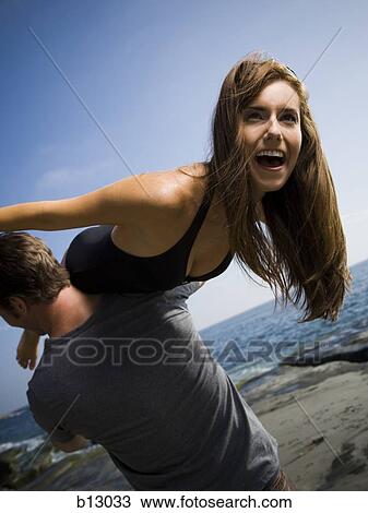Man carrying his girlfriend on beach View Large Photo Image Stock Image - Man carrying his girlfriend on beach. Fotosearch
