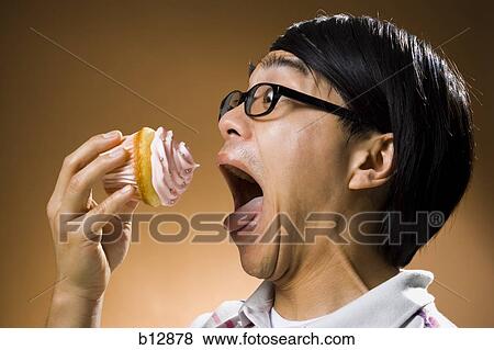 Man eating a cupcake View Large Photo Image Stock Photo - Man eating a cupcake. Fotosearch