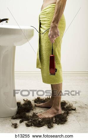 Stock Photography - Man in bath towel standing in hair with razor at bathroom sink. Fotosearch