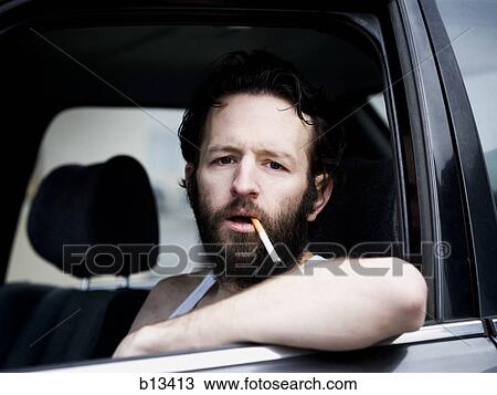 Man in car with cigarette hanging from mouth View Large Photo Image Stock Image - Man in car with cigarette hanging from mouth. Fotosearch