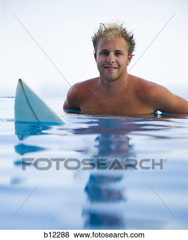 Stock Photo - Man in infinity pool with surfboard. Fotosearch