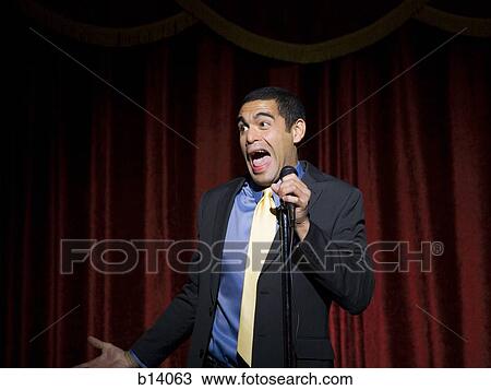 Stock Image - Man in suit with microphone making funny faces. Fotosearch