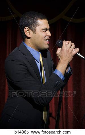 Stock Photography - Man in suit with microphone making funny faces. Fotosearch