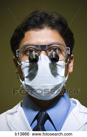 Stock Photograph - Man in surgical mask with microscopic glasses. Fotosearch