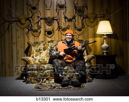 Man on sofa with rifle and antlers View Large Photo Image Stock Image - Man on sofa with rifle and antlers. Fotosearch