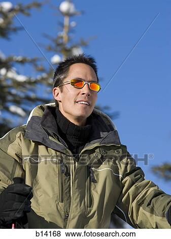 Man outdoors in winter with ski poles and sunglasses View Large Photo Image Stock Photo - Man outdoors in winter with ski poles and sunglasses. Fotosearch