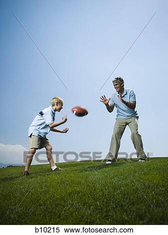 Man playing football with his son View Large Photo Image Stock Photography - Man playing football with his son. Fotosearch