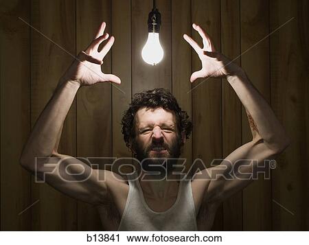 Stock Image - Man reaching to light bulb gritting teeth. Fotosearch