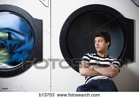 Man sitting in Laundromat with arms crossed watching dryer View Large Photo Image Stock Image - Man sitting in Laundromat with arms crossed watching dryer. Fotosearch