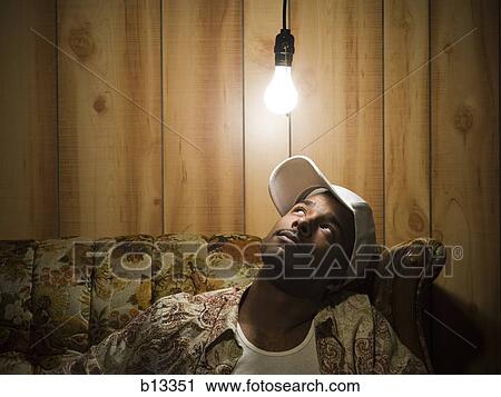 Man sitting on sofa looking up at light bulb View Large Photo Image Stock Image - Man sitting on sofa looking up at light bulb. Fotosearch