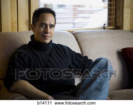 Man sitting on sofa smiling View Large Photo Image Stock Image - Man sitting on sofa smiling. Fotosearch