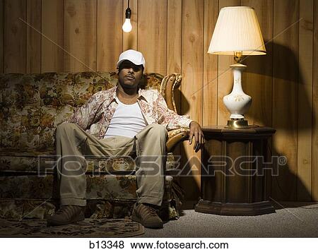 Man sitting on sofa under light bulb View Large Photo Image Stock Photo - Man sitting on sofa under light bulb. Fotosearch
